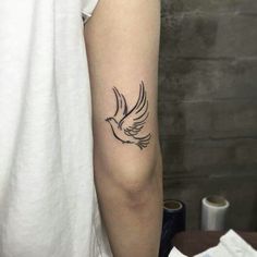 a woman's arm with a bird tattoo on the left side of her arm