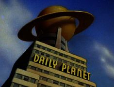 a tall building with a large yellow hat on it's top and the words daily planet above it