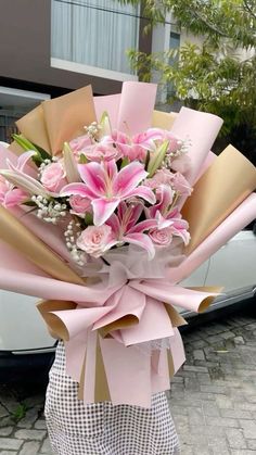 a woman holding a bouquet of flowers in front of a white car on the street