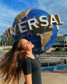 a woman standing in front of a sign that says universal with her hair blowing in the wind