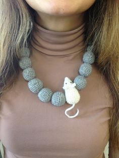 a woman wearing a crocheted necklace with a mouse on it