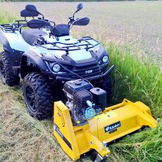 an atv parked in the middle of a field with a mower attached to it