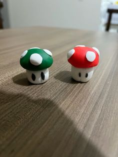 two small mushroom figurines sitting on top of a wooden table next to each other