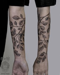 two people holding hands with tattoos on their arms and both have leaves tattooed on them