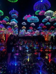 a person standing in front of an array of umbrellas that are lit up at night