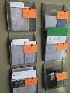 three metal bins holding files and folders with orange labels attached to the sides