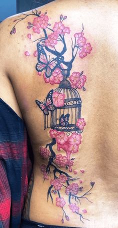 the back of a woman's body with pink flowers and a birdcage on it