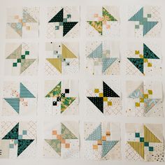 nine quilt blocks are arranged in rows on the wall, each with different designs and colors