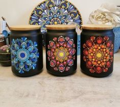 three jars with designs painted on them sitting on a counter