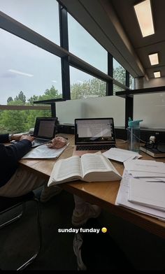 an open book sitting on top of a wooden desk next to a laptop computer and monitor