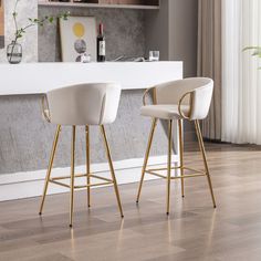 two white and gold bar stools in front of a counter