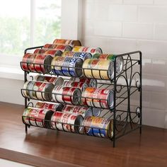 a rack with cans of canned food in it on a wooden floor next to a window