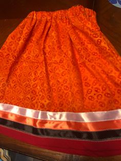 "Traditionally made Toddlers Ribbon skirt with black, orange and white ribbon work. Width is 44\", waist is 20\", length is 16 1/4\". Orange batik fabric with red bias tape on edging. Blessings!" Fitted Orange Cotton Skirt, Orange Fitted Cotton Skirt, Native Regalia, Ribbon Shirts, Ribbon Skirt, Ribbon Skirts, Ribbon Dress, Prayer Shawl, Ribbon Shirt