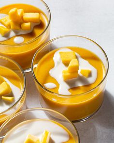 four glasses filled with different types of desserts on top of a white countertop