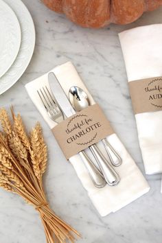 a place setting with silverware and napkins on a marble countertop next to some wheat stalks