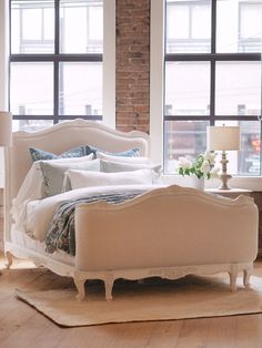 a white bed sitting next to a window in a bedroom on top of a hard wood floor