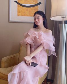 a woman in a pink dress sitting on a chair