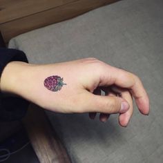 a small strawberry tattoo on the left hand