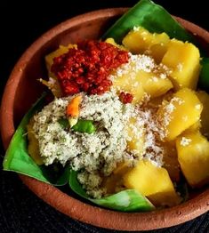 a wooden bowl filled with pineapples and other food on top of a table