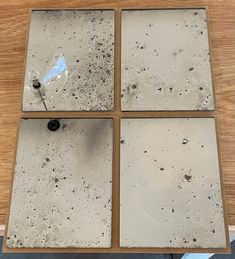 four square pieces of concrete sitting on top of a wooden table