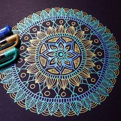 some pens are laying on top of a doily that is decorated with blue and gold designs