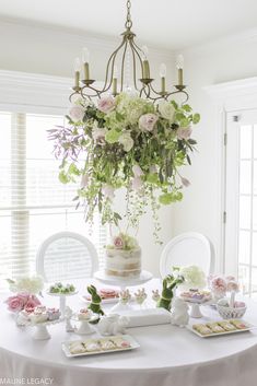 a white table topped with lots of food next to a chandelier filled with flowers