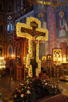 a cross decorated with flowers and candles in a church