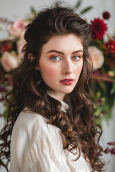 a woman with long hair wearing a white shirt and flowers in her hair is looking at the camera