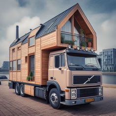 a large truck with a tiny house on the back is parked in front of a body of water