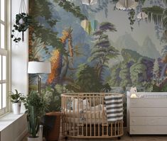 a baby's room with a crib, dresser and wallpaper that has a forest scene on it