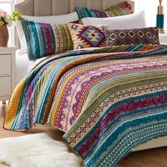 a bed with colorful bedspread and pillows