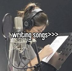 a woman sitting in front of a microphone with headphones on reading a piece of paper