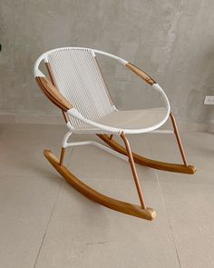 a white rocking chair sitting on top of a floor next to a potted plant