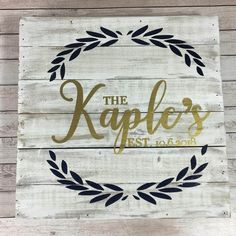 a wooden sign that says the kaples est to gord on it with an olive wreath