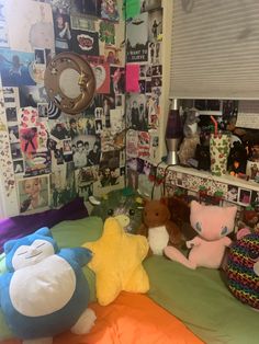 there are many stuffed animals on the bed in this room with pictures all over the wall