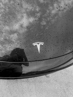 the hood of a car with a tesla logo on it's side window and clouds in the background