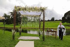 a man standing in front of a wedding arch with flowers on it and an aisle