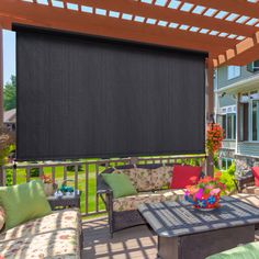 an outdoor living area with patio furniture and large black motorized shades on the window coverings