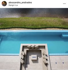 an aerial view of a swimming pool and lounge chairs in the foreground, looking down on a body of water