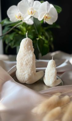 two white candles sitting on top of a table