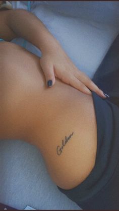 a woman laying on top of a bed with her stomach covered in tattoos and writing