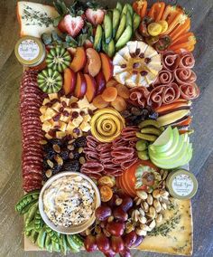 an assortment of fruits and vegetables arranged on a platter with dip sauce in the middle