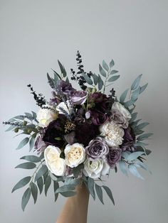 a bouquet of flowers in a vase with greenery on the top and purple, white, and lavender colors