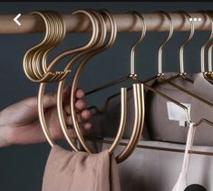 the person is trying to hang their clothes on a rack with gold colored metal bars