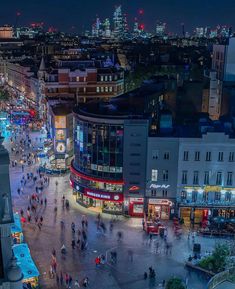 an aerial view of a city at night with lots of people walking around and buildings in the background