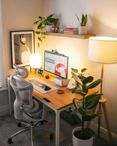 a desk with a computer, lamp and potted plant