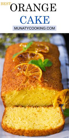 an orange cake is cut into slices and served on a white plate with green leaves