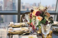 the table is set with gold plates and place settings