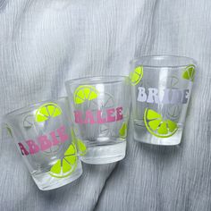 three personalized shot glasses with limes on the bottom and pink lettering that says bride