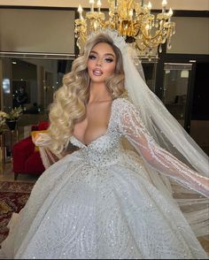 a barbie doll dressed in a wedding gown and tiara is standing next to a chandelier